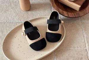 Gros plan détaillé de chaussures élégantes pour tout-petits avec bout contrasté et perle.