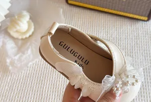 Primo piano di scarpe in pelle per bambini con elegante fiocco in pizzo e suola morbida.