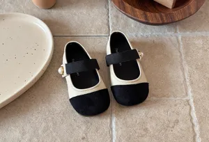 Gros plan sur les détails des chaussures plates princesse bicolores pour enfants.