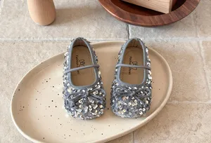 Gros plan détaillé de chaussures de princesse à paillettes grises avec nœud et bride élastique.