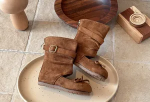 Detailed view of brown cutout suede mid-calf boots with cute bowknot and buckle decor.