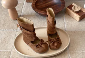 Detail view of brown suede kids mid boots with cute bow and split-toe design in spring.
