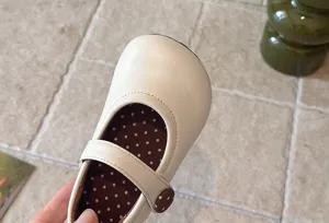 Detailansicht des cremefarbenen Kinderschuhs mit runder Kappe und gepunktetem Innenfutter.