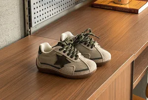 Close-up detail of khaki kids retro canvas trainers featuring star pattern and soft sole.