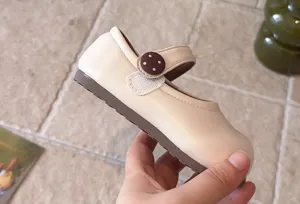Nahaufnahme von hellen Kleinkind Schuhen, weiche Sohle mit süßem gepunkteten Riemenknopf.
