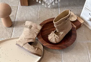 Detailed view of toddler girls cutout mid-calf boots in beige with bow and buckle design.