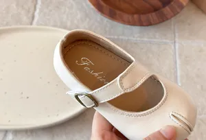 Detalle de zapato plano Mary Jane beige clásico con suela suave y hebilla retro para niñas.