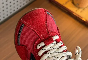 Detailed close-up view of kids red retro sneakers showing suede texture and white laces.
