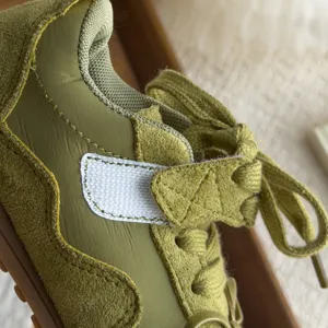 Détail de chaussures de sport rétro pour enfants, daim vert et textile avec de jolies coutures.