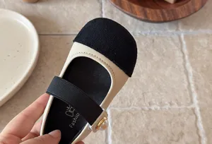 Détail de chaussures de princesse bicolores pour enfants, avec bout en suède et bride.
