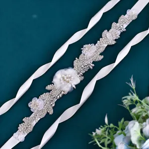 Handmade rhinestone bridal belt detail showing exquisite floral pearl beadwork on white ribbon.