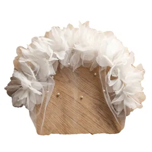 White tulle bridal face veil with delicate flowers and pearls, elegant wedding hair accessory.