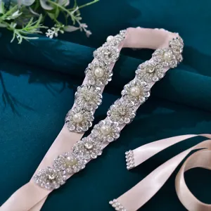 Dettaglio cintura da sposa in strass e perle, cristalli scintillanti su nastro di raso champagne.