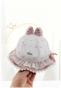 Vista dettagliata cappello sole neonato, motivo cuore, bordo pizzo, fiocco, tessuto morbido.