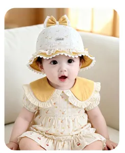 Primo piano dettagliato del cappello da bebè con fiocco giallo, bordo in pizzo e stampa floreale.