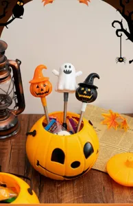 Halloween pumpkin candy bucket detail view with cute ghost and witch pens on wooden table.