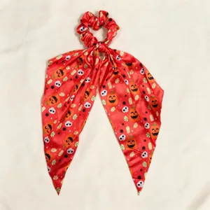 Halloween ribbon scrunchie detail view showing vibrant pumpkin and skull print pattern.