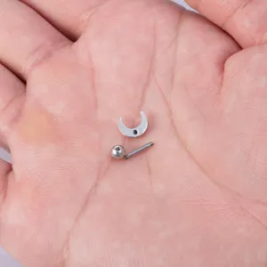 Detailweergave van een roestvrijstalen maanvormige oor piercing en kraakbeen stud.