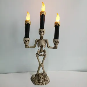 Halloween skeleton LED candle holder with three black dripping wax candles and gothic skull base.