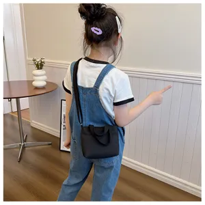 Détail du mini sac cabas en nylon pour enfants, sac à bandoulière noir compact et pratique.