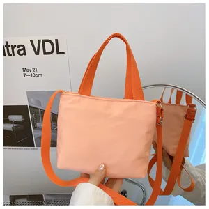 Vue rapprochée du mini sac cabas en nylon pêche avec anses et bandoulière en toile.