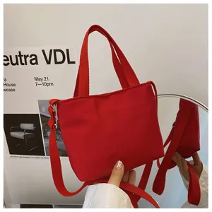 Détail de mini sac cabas en nylon rouge avec bandoulière et design compact pour un usage quotidien.