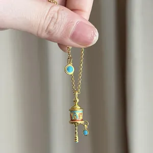 Tibetan style golden prayer wheel necklace with turquoise and red enamel accents for women
