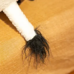 Close-up detail of the cute cow plush toy tail, showing soft texture and fine stitching.