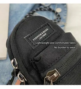 Mini schwarze Stoff Umhängetasche Detail mit Reißverschlusstasche und Modelabel.