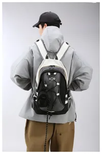 Detailansicht des modischen Kontrastfarben-Rucksacks mit hängender Minitasche und Kordeln.