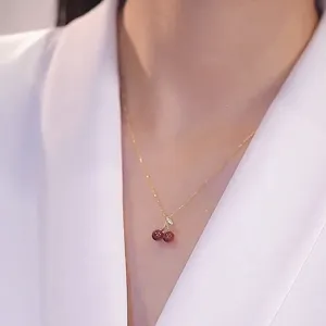 Detail shot of the red cherry pendant necklace, elegant gold chain collarbone jewelry.