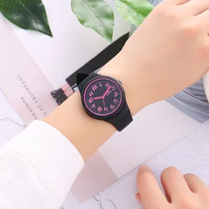 Close-up of black silicone watch on wrist with pink numbers and clean marble background scene.