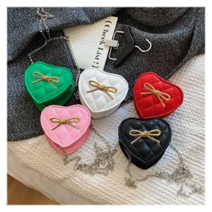Λεπτομερής εικόνα από πολύχρωμες καπιτονέ παιδικές τσάντες χιαστί σε σχήμα καρδιάς με φιόγκο.