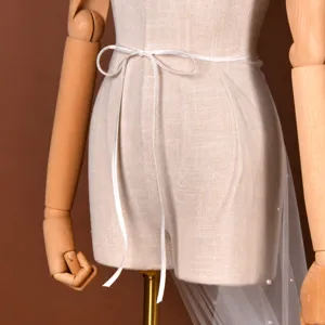 Detachable bridal mesh overskirt with pearls and ribbon tie, perfect for wedding dresses.