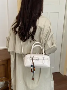 Chic white leather Boston bag for women, featuring a trendy belt buckle and pendant.