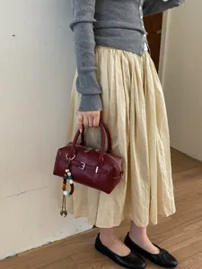 Chic burgundy boston handbag for women, stylish leather shoulder bag with buckle and charm.