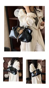 Black glossy slouchy shoulder tote bag for women with chic woven heart charm detail.