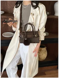 Detail view of brown leather shoulder handbag featuring woven texture and chic pendant.