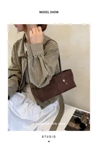 Brown suede shoulder bag detail showing premium texture, elegant underarm style and chic key charm.