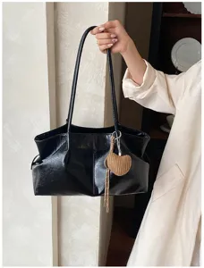 Detail of black PU leather shoulder tote bag with pleated design and cute heart straw pendant.