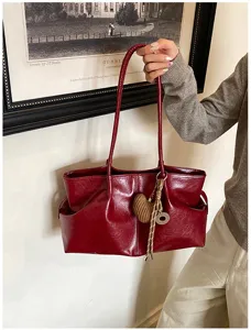Detail view of the red glossy leather tote bag with woven heart charm and side pockets.