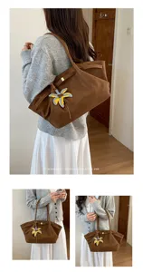 Detailed view of brown casual shoulder tote bag with unique palm leaf charm, stylish design.