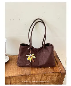 Close-up detail of the elegant brown suede tote bag with double straps and palm charm.