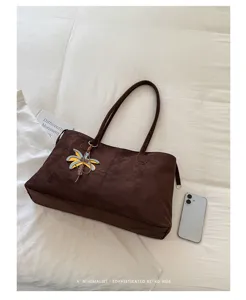 Detailed view of the soft brown suede tote bag featuring a palm tree charm and large capacity.