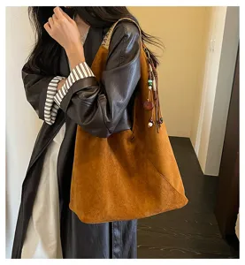 Brown suede slouchy shoulder bag detail, vintage hobo dumpling bag with chic tassel charm.