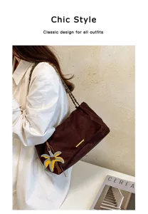 Detailed view of the chic brown suede shoulder bag with chain strap and palm charm.