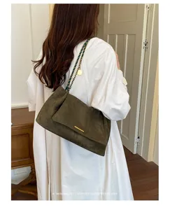 Green suede underarm bag detail, soft velvet texture, retro chain strap for chic style.