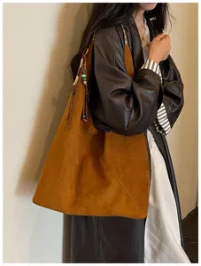 Detail view of a retro brown suede hobo dumpling bag with chic tassel and beaded charm.
