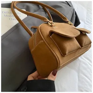 Detailed view of brown retro shoulder bag with dual front pockets, showing premium texture.