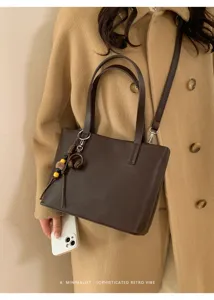 Vista dettagliata della borsa shopper marrone minimalista con texture pregiata e ciondolo chic.